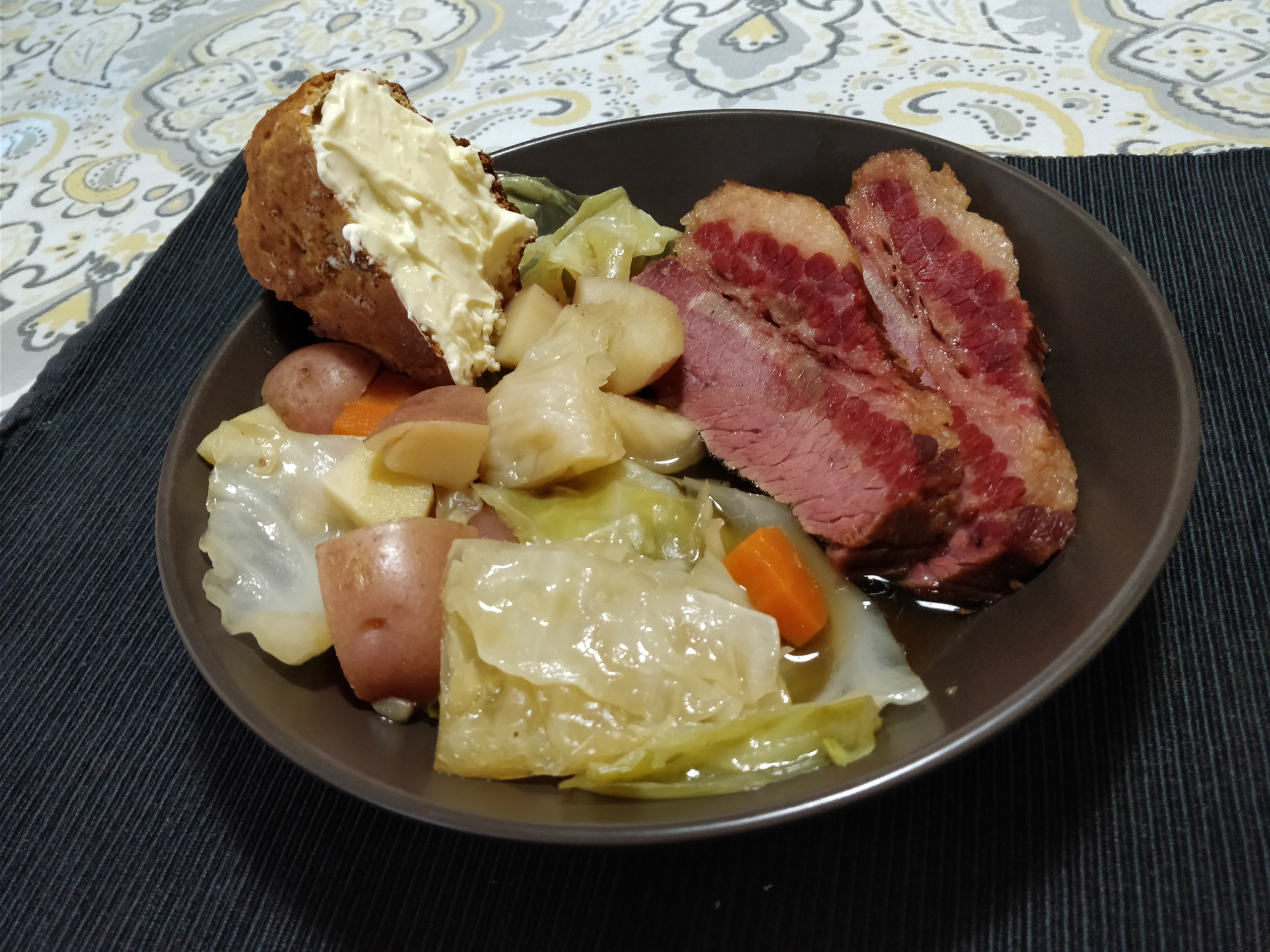 plate of corned beef, cabbage, potatoes, carrots, parsnip, and heavily-buttered soda bread