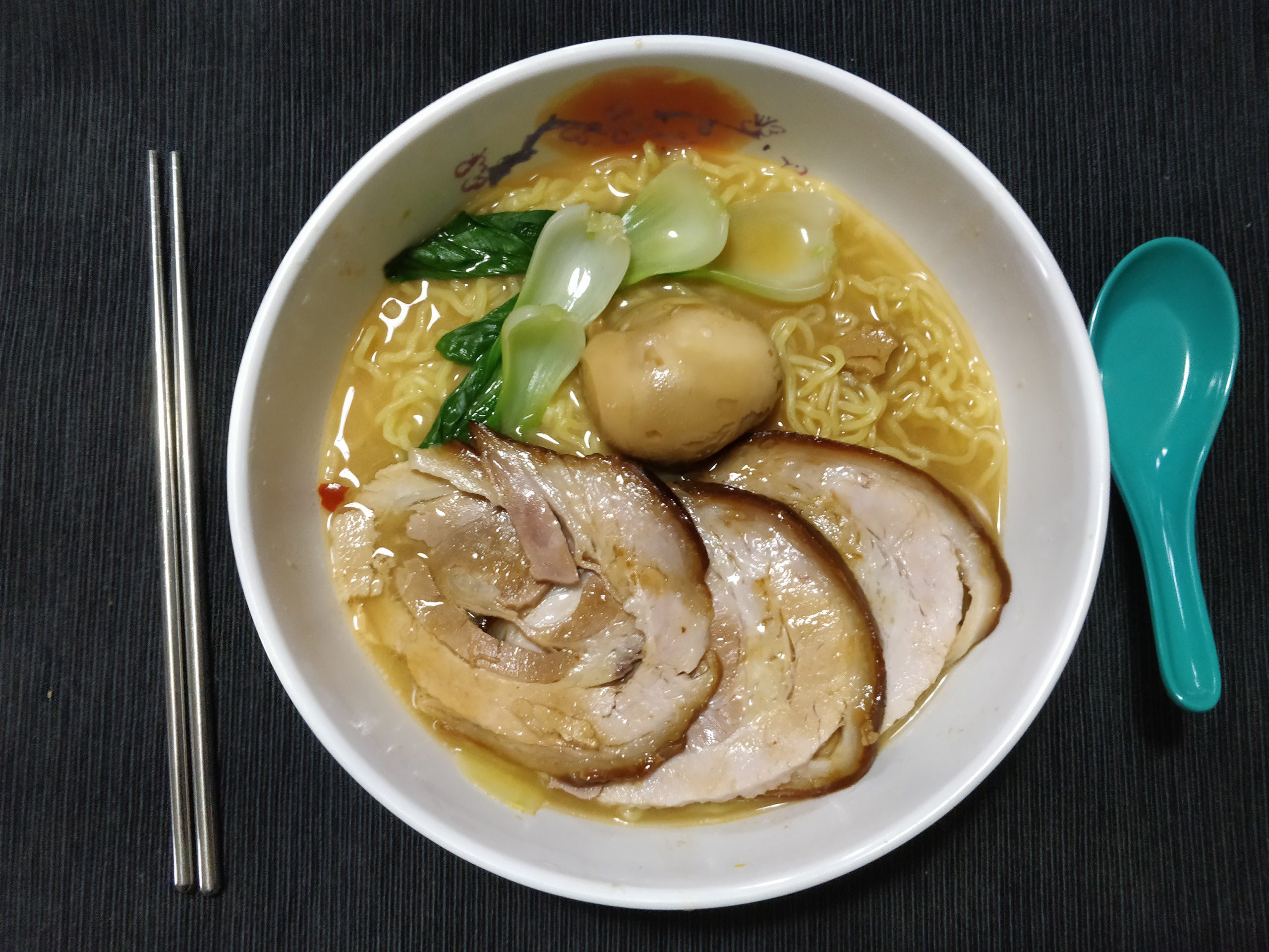 bowl of miso ramen featuring chashu pork, marinated bok choy (ohitashi), and a marinated egg