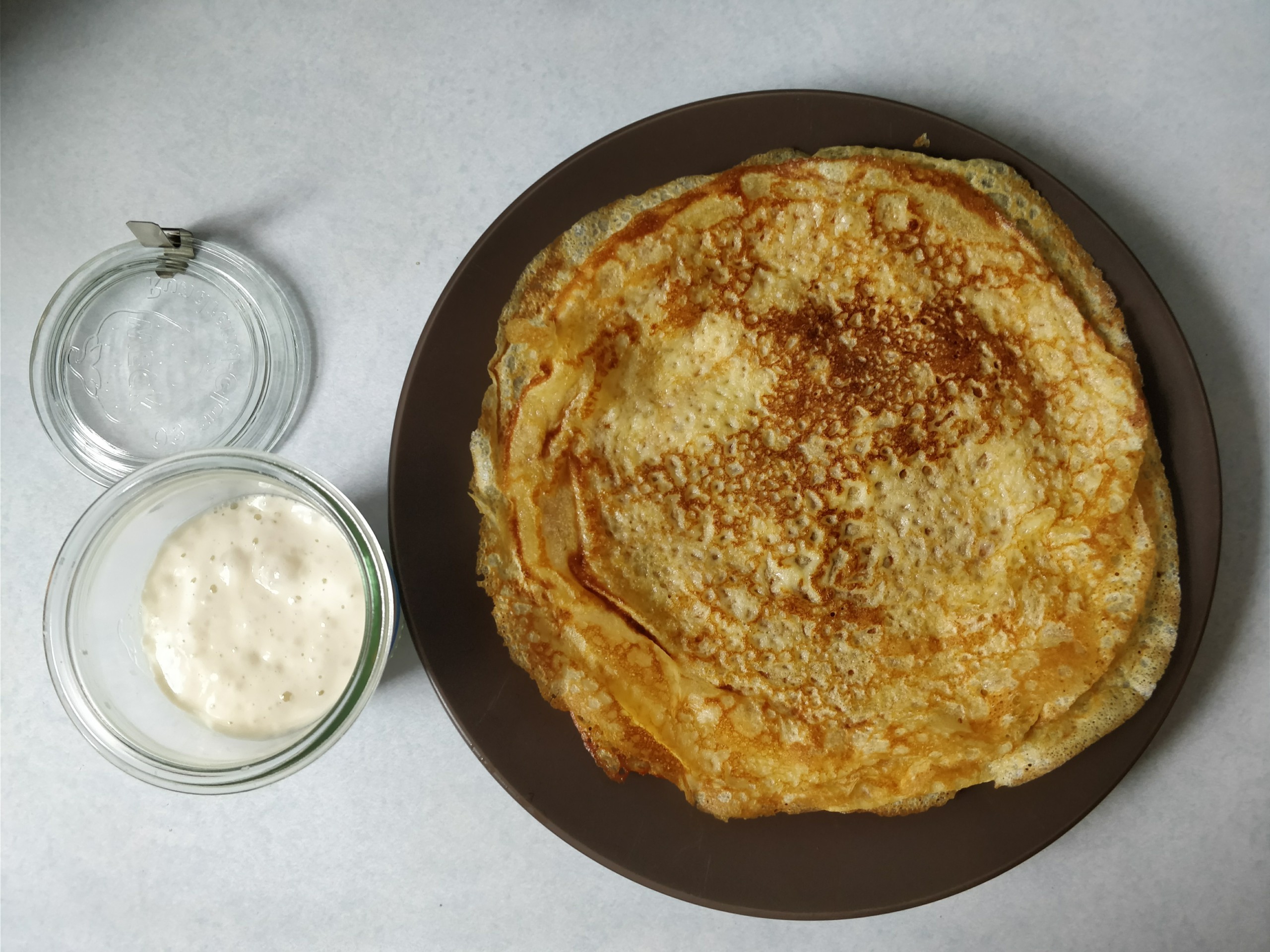 plate of sourdough crepes next to an open weck jar containing sourdough starter