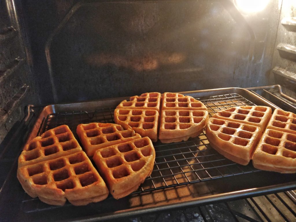 Three sourdough waffles on a rack in the oven.