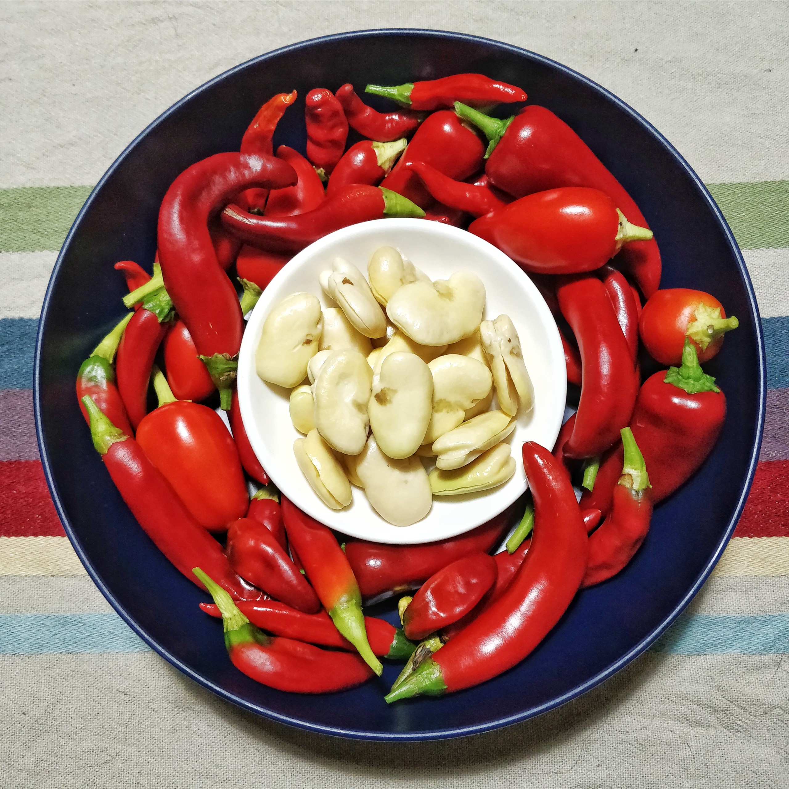 Bowl of chilies with a smaller bowl of fava beans nestled inside.