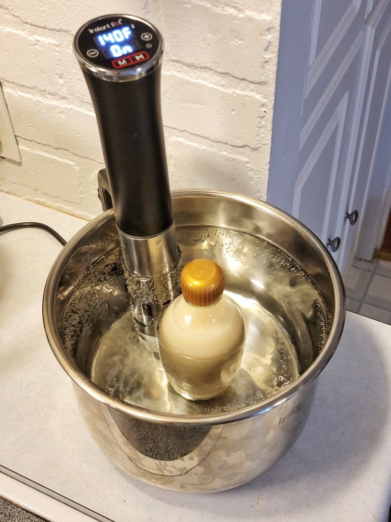 Bottle with loosened cap in a water bath, immersion circulator holding water at 140°F.