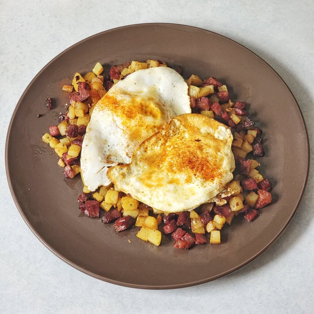 Corned beef hash with 2 eggs on top and a dash of paprika.