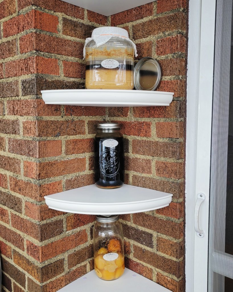 Corner shelves on a brick wall, each with a single large jar.