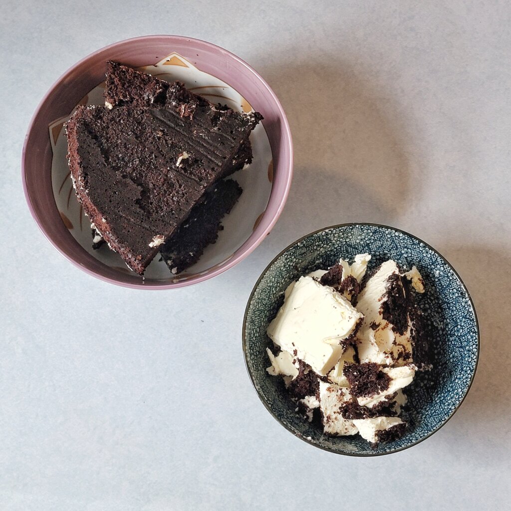 A bowl with naked cake next to a bowl of scraped-off frosting.