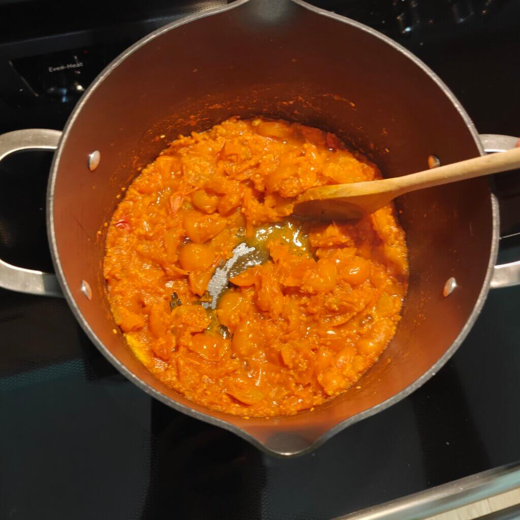 The tomatoes have been cooked down to the point where the liquid no longer pools when moved aside with a spoon.
