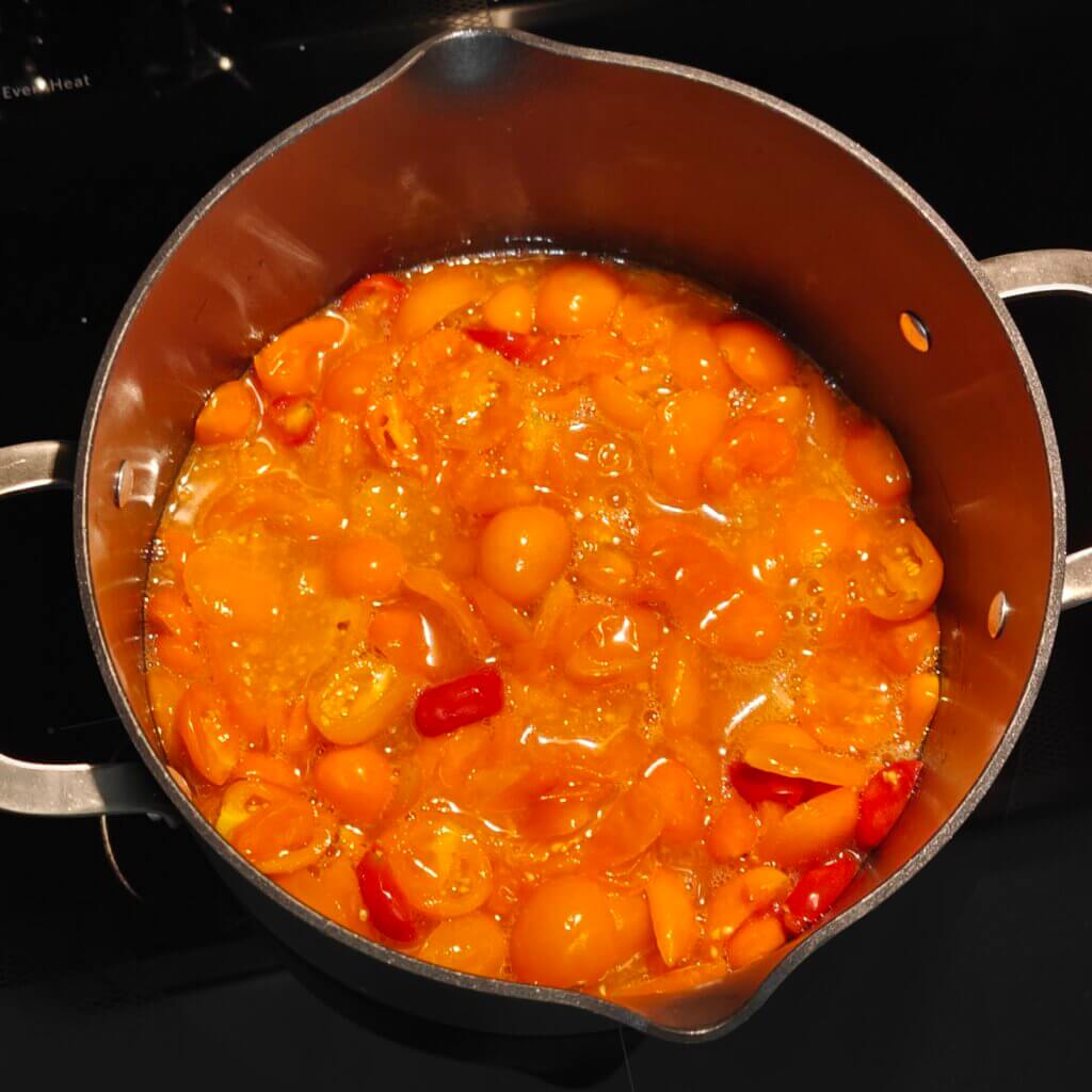 Fermented cherry tomatoes in a saucepan just starting to heat up.