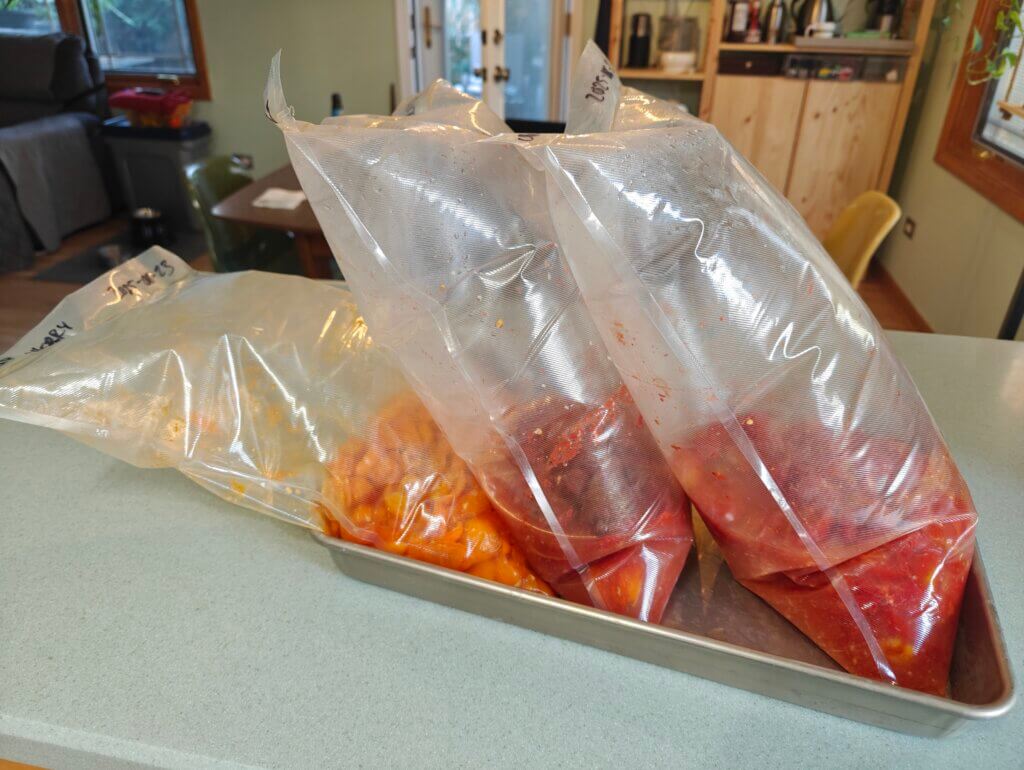3 very puffy vacuum bags in an aluminum tray on the counter.