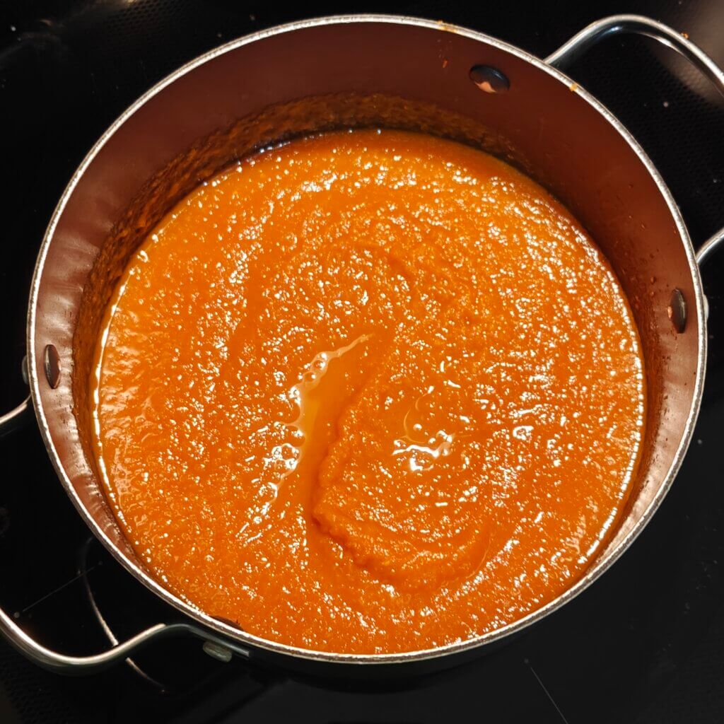 Tomato pulp added back to the pot. Thinner liquid is pooling on top.